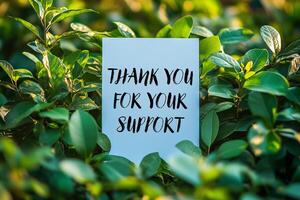 Thank you for your support message written on white card on a bush photo