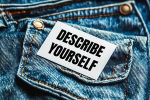 Describe yourself message written on white card on denim jean background. Conceptual describe yourself symbol. Copy space. photo