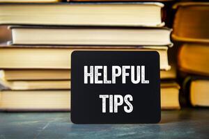 Helpful tips message written on black card with stack of books. Conceptual helpful tips symbol. Copy space. photo