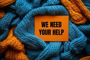 We need your help message written on orange card on fabric background. Conceptual we need your help symbol. Copy space. photo