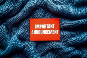 Important announcement message written on orange card on blue fabric background. Conceptual important announcement symbol. Copy space. photo