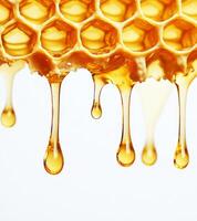 Golden honey drips from honeycomb against white background, showcasing natural sweetness and texture of honey. close up view highlights hexagonal pattern and rich, amber color photo