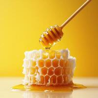 honey dipper drizzles golden honey over fresh honeycomb against vibrant yellow background, creating sweet and appetizing scene photo