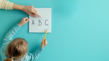Working mom helps with homework and teaching. Child learning letters with adult guidance on blue background photo
