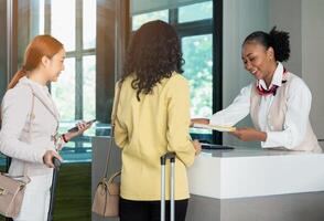 Smiling African airline ground attendant in uniform handing ticket documents to tourist at airport check in desk photo