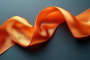 A long orange ribbon is curled up on a dark surface photo