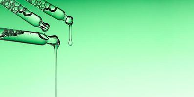 Pipette serum drop with niacinamide, hyaluronic or Aha Bha acids on a green isolated background photo