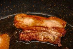 Sizzling pork belly cooking to crispy perfection in a hot skillet for a delicious meal photo