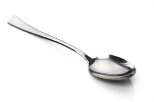 Shiny silver spoon resting on a smooth white surface, glistening under soft light photo