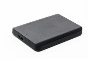 Portable external hard drive resting on a white surface, ideal for data storage and backup solutions photo