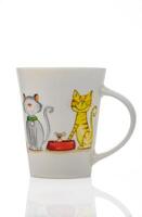 Whimsical ceramic mug featuring playful cats and a mouse in a cozy kitchen setting photo