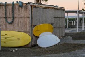 Colorful surfboards lean against a rustic beach shed at twilight by the ocean photo