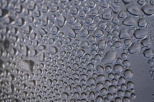 Raindrops gather on a window pane, creating a mesmerizing pattern of nature's artwork at dawn photo