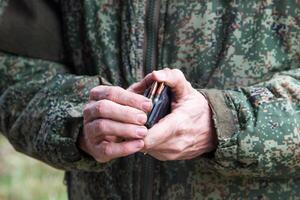Soldier hands load rifle machine gun bullets into cartridge clip photo