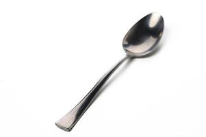 Elegant stainless steel spoon resting on a white surface with a subtle shine captured in soft light photo