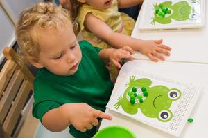 A child collects a puzzle for the development of fine motor skills photo