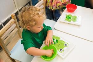 A child collects a puzzle for the development of fine motor skills photo