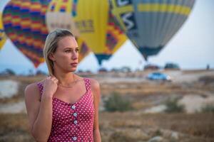a girl is walking against the background of balloons in cappadocia photo