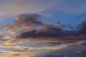 Dramatic evening sky filled with colorful clouds over a tranquil landscape at sunset photo