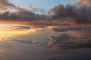 Vibrant sunset skies filled with dynamic clouds over a tranquil horizon photo