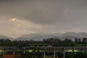 Dark clouds gather over serene mountains as rain approaches in the late afternoon sky photo