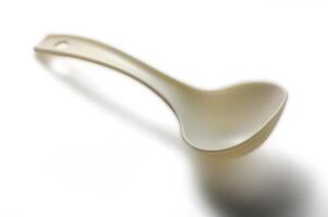 Unique plastic ladle with a minimalist design resting on a smooth surface photo