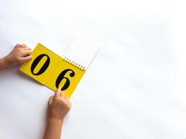 Child flipping calendar on white background with number 06 displayed photo