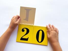 Childs hands flip through yellow pages with numbers on a white background photo