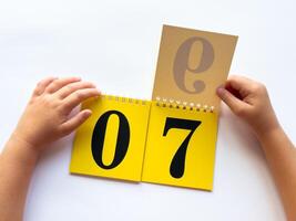 Child learning numbers with interactive flip calendar on white surface photo