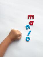 Childs fist arranged with colorful letters manic on white background photo