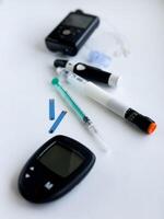 Diabetes management tools, glucose meter, insulin pen, and pump on white surface photo