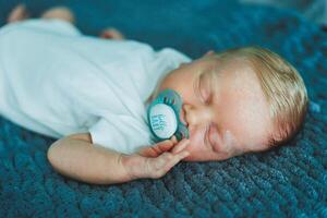 Portrait of a sleeping baby. A newborn baby is sleeping. A baby in a white cotton bodysuit photo