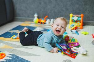 A 4-month-old boy lies on a mat and crawls. The baby lies on a thermal mat and plays. Self-development of a newborn child. Toys for child development. photo