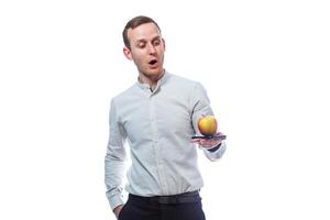 Caucasian male businessman holding a mobile phone in black and holding a red-yellow apple. He is wearing a shirt. Emotional portrait. Isolated on white background photo