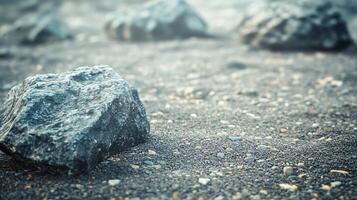 Large rock sits on a sandy beach. The rock is surrounded by smaller rocks and pebbles, creating a sense of depth and texture. The scene evokes a feeling of solitude and tranquility photo