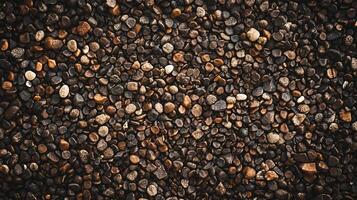 Close up of a pile of rocks with a brownish color. The rocks are scattered all over the ground and some of them are larger than others. The image has a natural and earthy feel to it photo