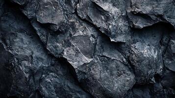 Close up of a rock wall with a dark blue color. The wall is made of large rocks and has a rough texture. Concept of ruggedness and strength, as the rocks seem to be unyielding photo
