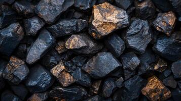 Pile of rocks with a golden hue. The rocks are black and shiny, and they appear to be from a quarry. Concept of ruggedness and strength, as the rocks are solid and unyielding photo