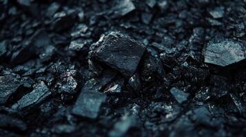 Close up of a pile of black rocks. The rocks are small and scattered, with some of them being larger than others. The image has a dark and moody atmosphere, with the rocks appearing almost ominous photo