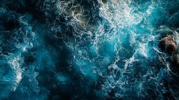 The image is of a body of water with waves and foam. The water appears to be blue and the foam is white. Scene is calm and peaceful, as the water seems to be still and the foam is gentle photo