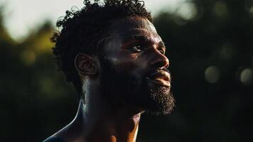 Man with a beard and dreadlocks is sweating in the sun. He is looking up at the sky photo