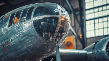 Silver airplane with a large window on the front. The airplane is in a hangar. The hangar is dark and the airplane is the only thing visible photo