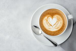 Creamy coffee with heart shaped latte art served in a white cup on a light surface photo