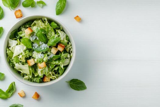 Fresh green salad with croutons and herbs served in a rustic bowl on a wooden table photo