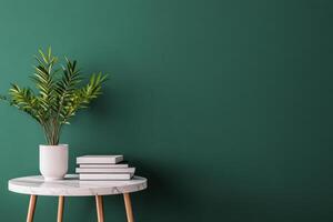 Elegant desk setup with books and greenery beside dark green wall photo