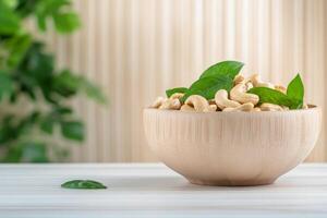 Cashews in a wooden bowl on a table surrounded by greenery during daylight photo