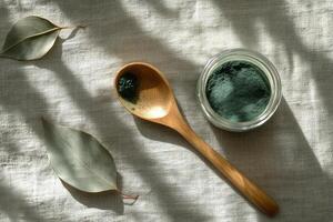 Natural green powder and leaves arranged on fabric surface in bright light photo
