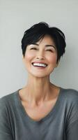 Woman with short black hair smiling warmly in a relaxed indoor setting during daylight photo