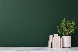 Elegant desk setup with books and greenery beside dark green wall photo