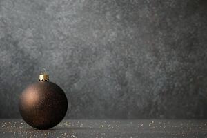 Black ornament resting on a surface with golden glitter against a textured background photo